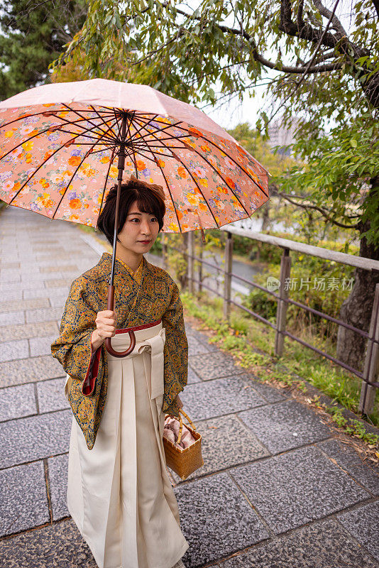 穿着和服/袴的年轻女子在下雨天走在城里